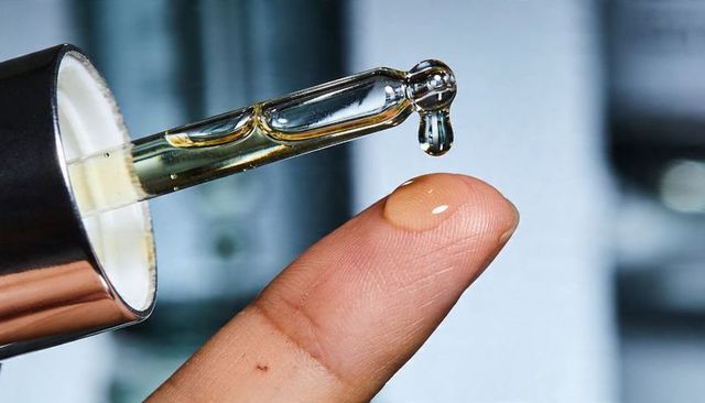 Closeup dropper delivering skincare serum onto finger for luxury beauty routine