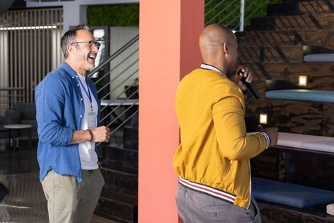 Diverse male coworkers presenting and laughing in modern collaborative lounge