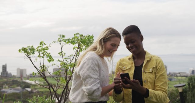 Friends Outdoors Smiling and Looking at Smartphone Together - Download Free Stock Images Pikwizard.com