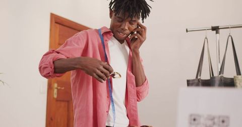 Creative african american craftsman making phone call while organizing belts
