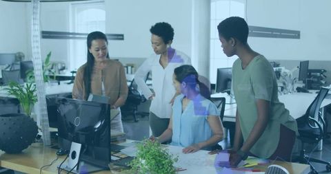 Diverse team analyzing blueprints in modern office