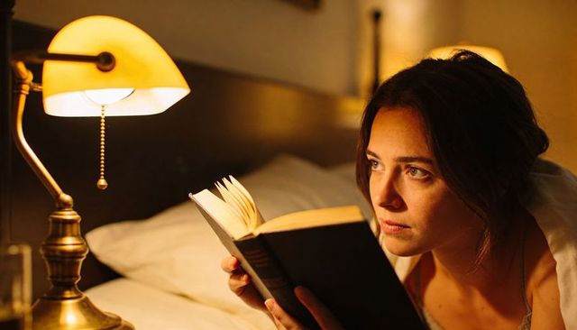Woman Reading in Bed by Brass Lamp Warm Amber Glow Cozy Nighttime Portrait