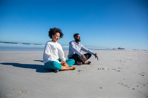 Couple Meditating on Seaside Sandy Shore for Relaxation and Wellness