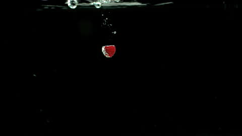Close-up of Raspberry Plunging into Water on Black Background
