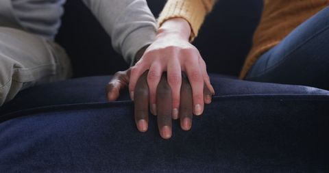 Interracial Couple Holding Hands on Sofa, Embracing Connection and Unity