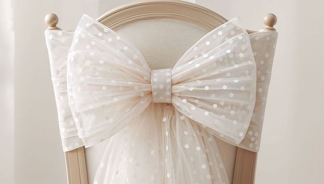 Polka-dot tulle bow draping elegant wooden chair back for wedding reception
