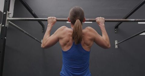 Determined Woman Performing Chin Ups in Gym Environment