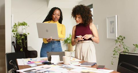 Women collaborating on branding moodboard and digital designs in bright home office