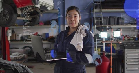 Female mechanic using laptop for digital vehicle diagnostics in high-tech garage