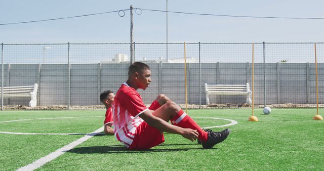 Diverse male football players training and doing sit-ups on outdoor pitch - Download Free Stock Photos Pikwizard.com