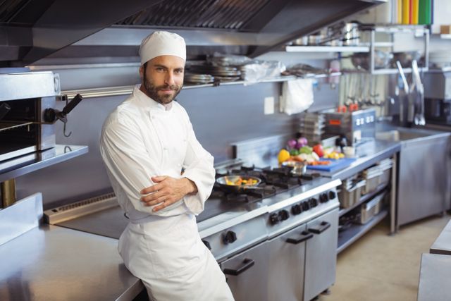 Chef standing confidently in a modern commercial kitchen, perfect for illustrating professional culinary environments, restaurant advertisements, hospitality industry promotions, and cooking class materials.