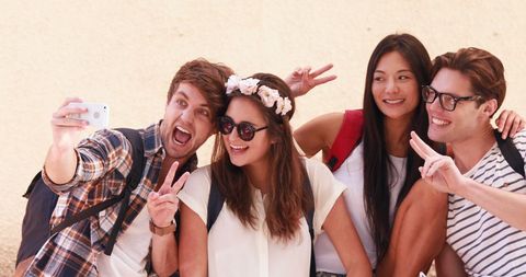 Joyful friends taking selfie outdoors with peace signs