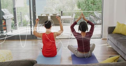 Couple meditating at home on yoga mats facing glass doors morning light wellness routine