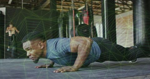 Dedicated man training in boxing gym with push-up exercise