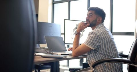 Man contemplating in modern office with laptop and robotic arm