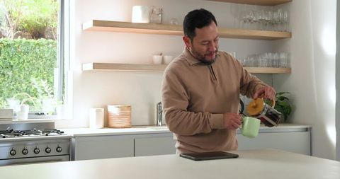 Man Pouring Coffee in Modern Minimalist Kitchen