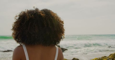 African American Woman with Curly Hair Standing by Ocean