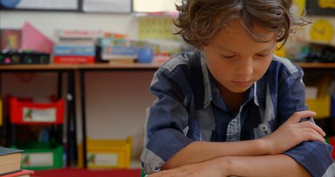 Young Boy Focused on Reading Book in Classroom - Download Free Stock Images Pikwizard.com