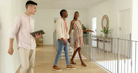 Happy couple with estate agent in bright modern home