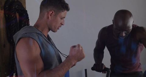 Coach Motivates Client on Stationary Bike in Gym