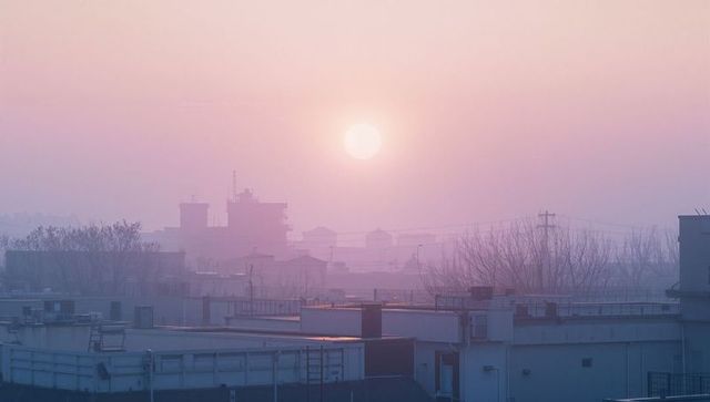 Rising Pastel Sunrise Casting Mist Over Urban Rooftops With Chimneys, Vents, Power Lines