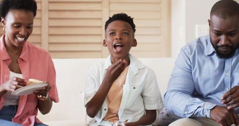 African American family sharing snacks on sofa, parents and son enjoying cupcake moment