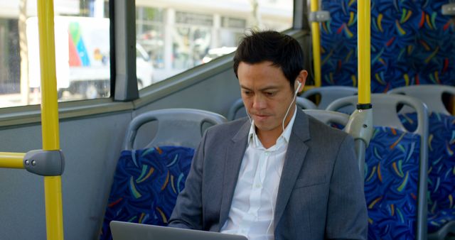 Business professional wearing a suit, commuting on a bus while working on laptop. Ideal for promoting mobile working, public transportation, productivity during commute, or urban lifestyle.