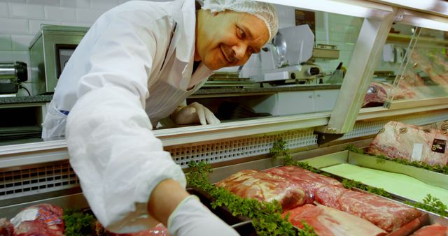 A middle-aged Caucasian butcher is arranging meat products in a display case, with copy space. His expertise and care ensure that the selection of meats is presented appealingly to customers.