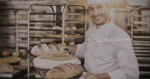 Smiling baker carrying peel of freshly baked sourdough loaves in busy artisan bakery