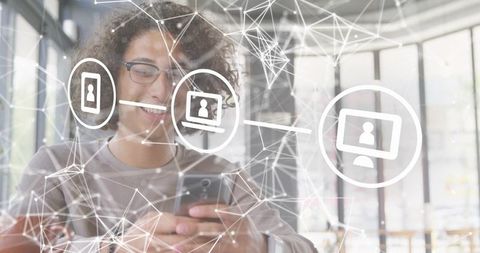 Young man using smartphone in coworking space with digital network overlay and icons