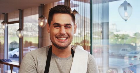 Barista Smiling in Cafe Setting with Towel and Apron