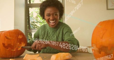 Laughing woman carving pumpkins at home for cozy halloween celebration