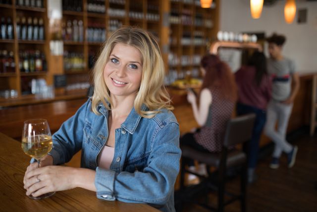 Portrait of smiling beautiful woman having wine at counter in bar