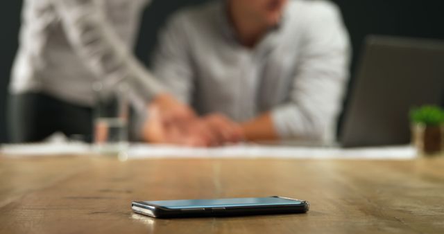 Smartphone on Wooden Table with Businesspeople in Background - Download Free Stock Images Pikwizard.com