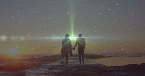 Romantic couple walking hand in hand at sunset seaside