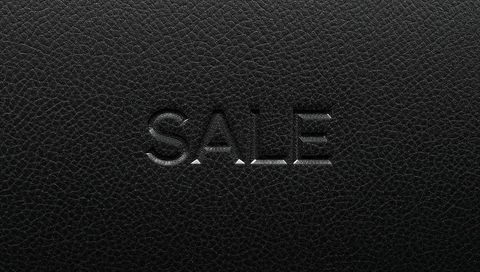 Embossed sale text on black pebbled leather with glossy inner edges and debossed texture