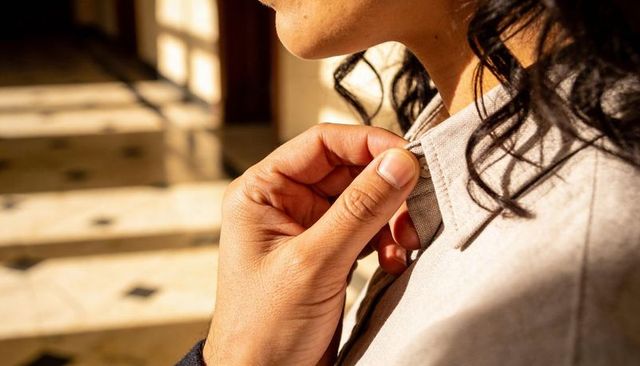 Adjusting collar gesture showing tender connection between couple in sunlit foyer