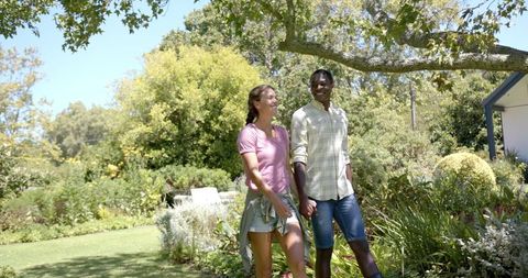Diverse Couple Walking Hand in Hand in Lush Garden Scene - Download Free Stock Images Pikwizard.com