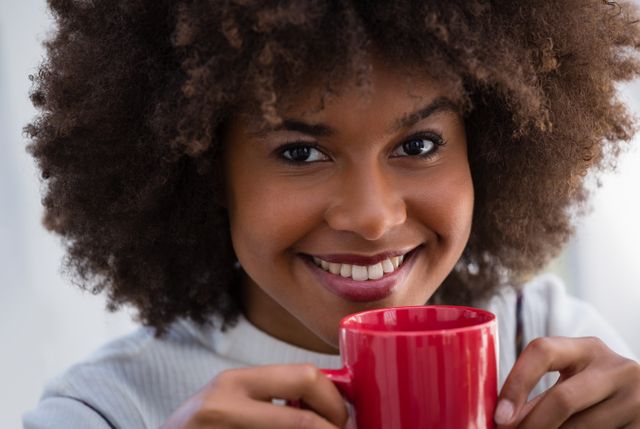 Close up portrait of smiling woman with frizzy hair holding coffee mug in cafe
