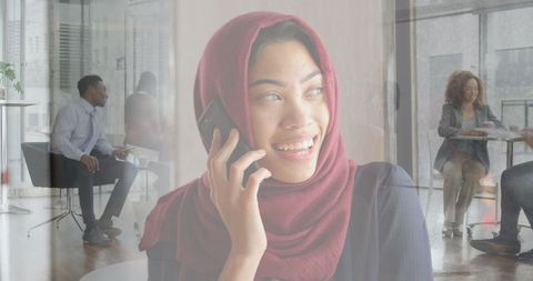 Smiling Businesswoman in Hijab Talking on Phone in Modern Office