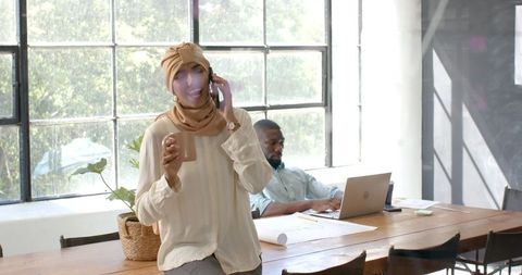 Woman in hijab enjoying coffee break in office
