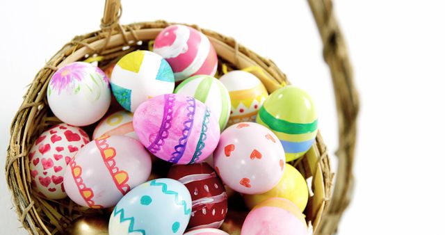 A wicker basket is filled with colorful, decorated Easter eggs, showcasing a variety of patterns and designs, with copy space. These eggs symbolize the celebration of Easter and the tradition of egg decoration.