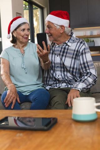 Senior couple enjoying festive video call with santa hats