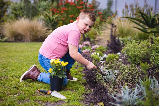 Caucasian boy holding a shovel gardening in the garden outdoors. childhood, hobby and gardening concept