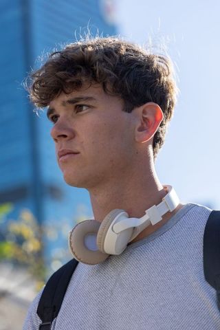 Backlit urban teen portrait wearing headphones and backpack looking left for lifestyle
