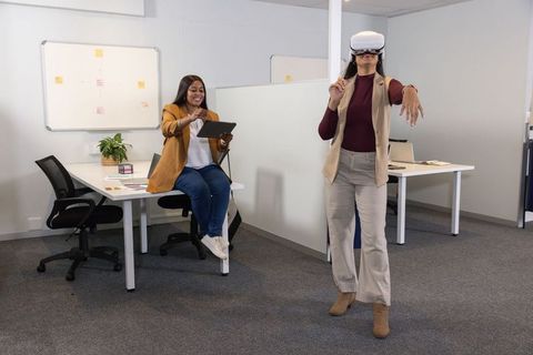Colleagues testing vr design while coworker controlling ar tablet in modern office