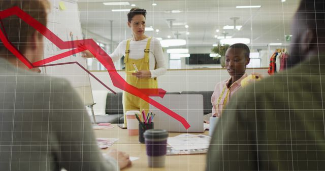 Business presentation showing a declining financial chart, featuring a businesswoman addressing diverse colleagues in a modern, open office space. Useful for illustrations of market downturns, teamwork, motivation, financial discussions, and collaborative workplace scenarios.