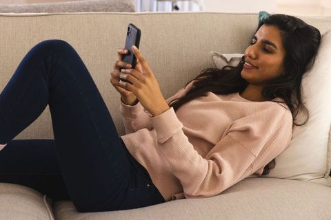 Woman Relaxing on Sofa with Smartphone in Cozy Home Environment