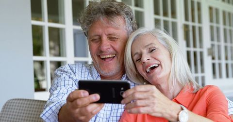 Joyful Senior Couple Taking Selfie with Smartphone at Home