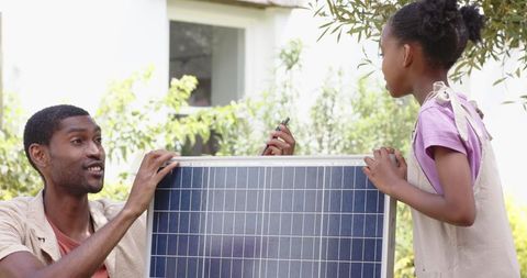 Father Teaching Daughter About Renewable Energy with Solar Panel Outdoors